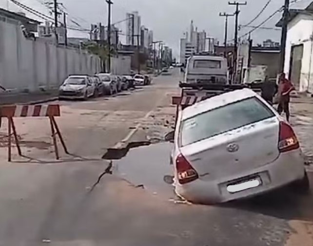 Carro é engolido por cratera aberta após tubulação de água se romper na Avenida Miguel Castro