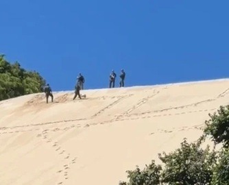 Policiais militares e guarda ambiental apagam sigla 'SDC' escrita na areia do Morro do Careca