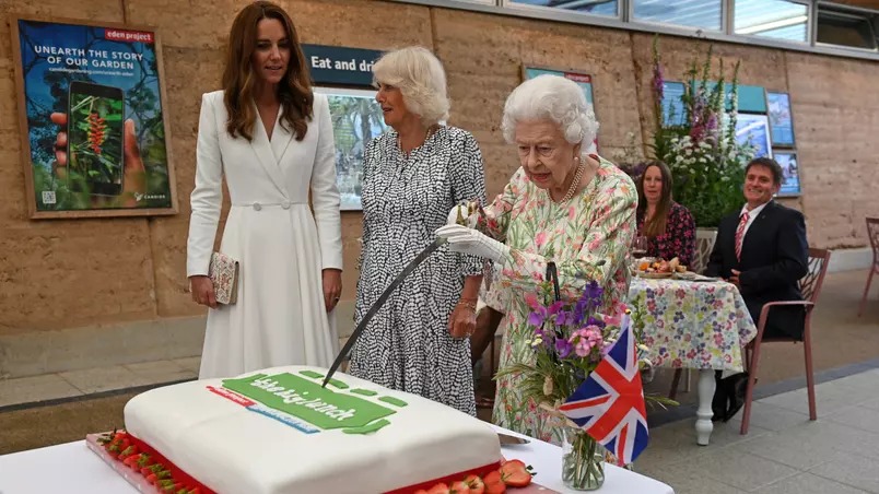 Rainha Elizabeth despedaça bolo com uma espada durante evento