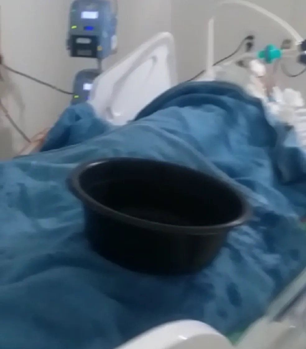 Funcionários colocam bacia sobre maca de paciente para conter goteira em hospital de Mossoró