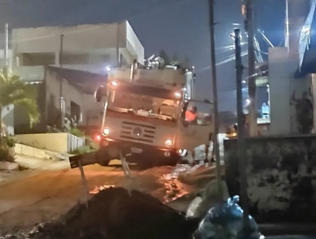 Carro de coleta de lixo fica preso em buraco em rua de Natal